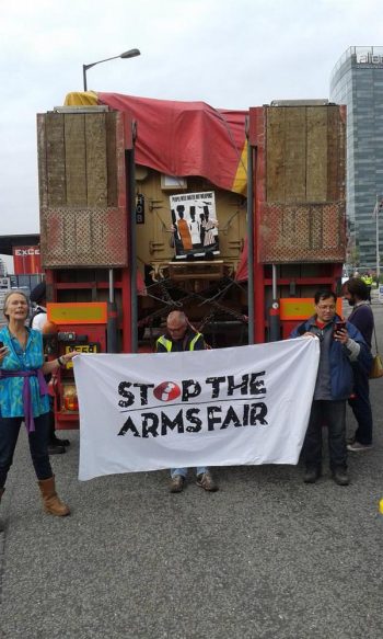 Activists hold a 'Stop the Arms Fair' banner in front of an armoured vehicle