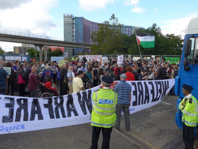 A crowd of protesters block vehicle from entering DSEI