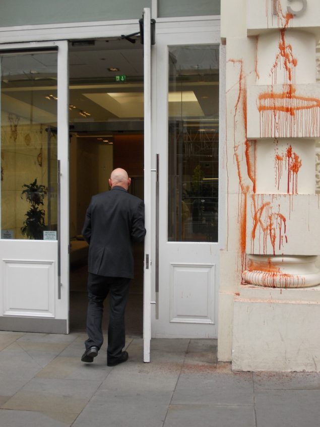A person walks into a building alongside a white wall painted red