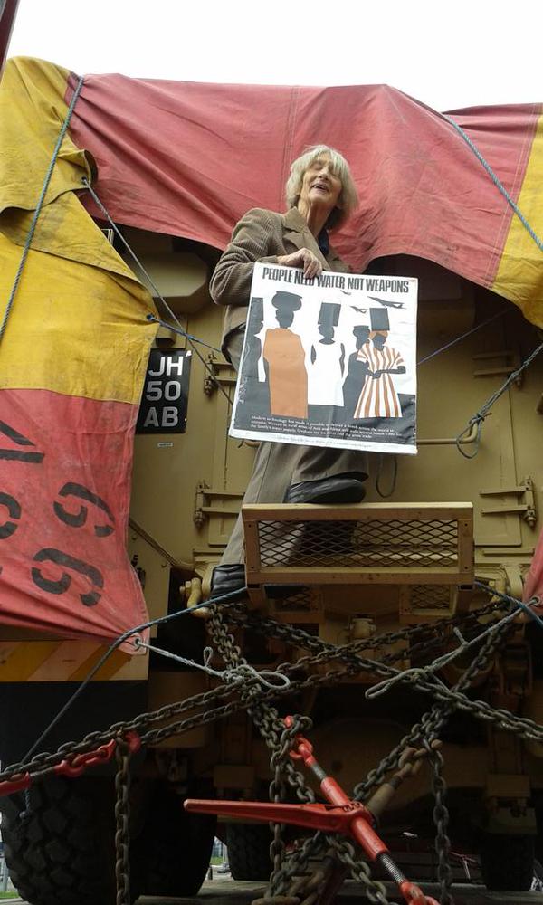 An activist stands on an armoured vehicle holding a placard
