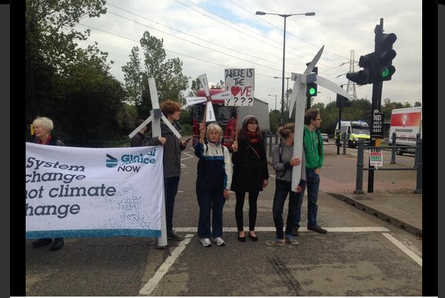 Five people blockade a road while holding wind turbines