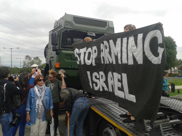 Activists hold a 'Stop Arming Israel' banner on a military vehicle