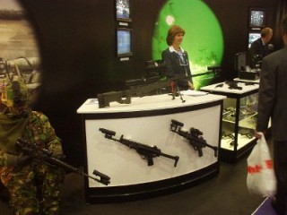Woman stands behind display stall covered with guns